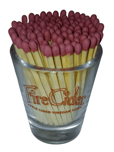 Glass Fire Cider shot glass with matches - The Creative Shed - The Creative Shed - Glass filled with red matches labeled 'Fire Cider Apple Cider Vinegar Tonic' on a white background - 