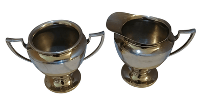 Metal creamer and sugar containers - The Creative Shed - The Creative Shed - Two silver Metal creamer and sugar containers with handles on a white background - 