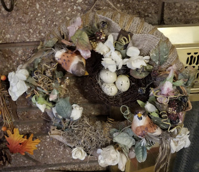 Spring wreath with birds and nest. - The Creative Shed - The Creative Shed - A round spring wreath with birds and a nest, decorated with white and yellow flowers, green leaves, and brown branches. - 