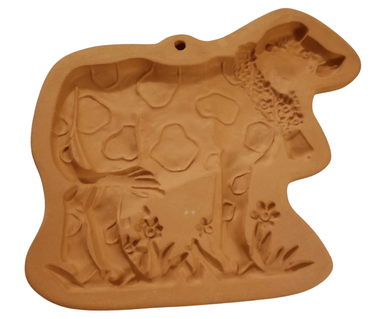 Terra Cotta Cookie Mold/Cow - The Creative Shed - The Creative Shed - A terracotta cookie mold in the shape of a cow standing on a field with flowers. - 